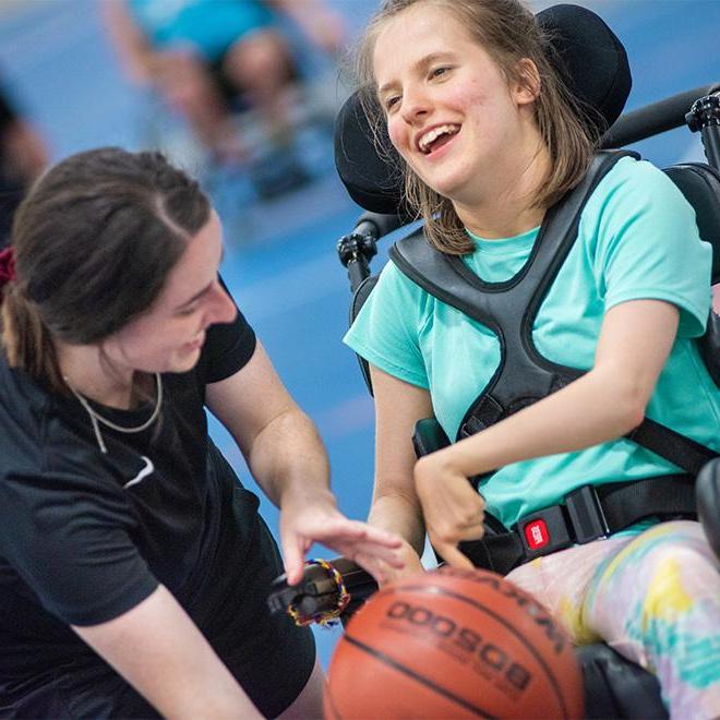 Students working with kids with Disabilities playing basketball