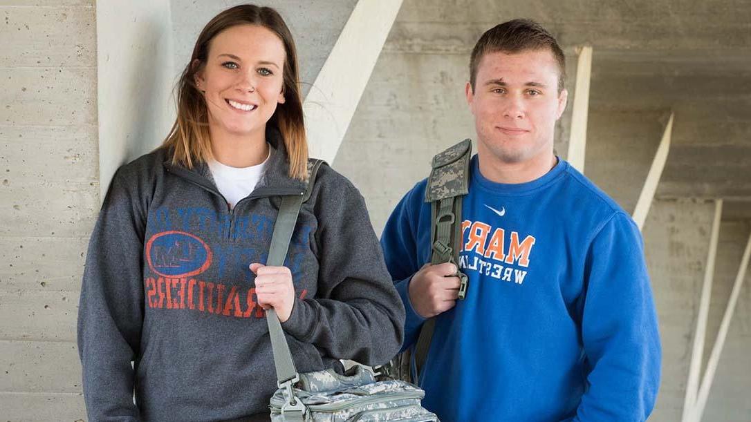 Two smiling military students carrying camouflage backpacks